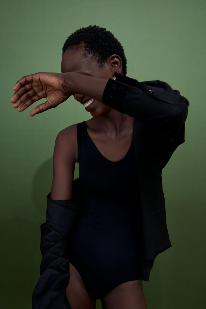 a black female model smiling and covering her face